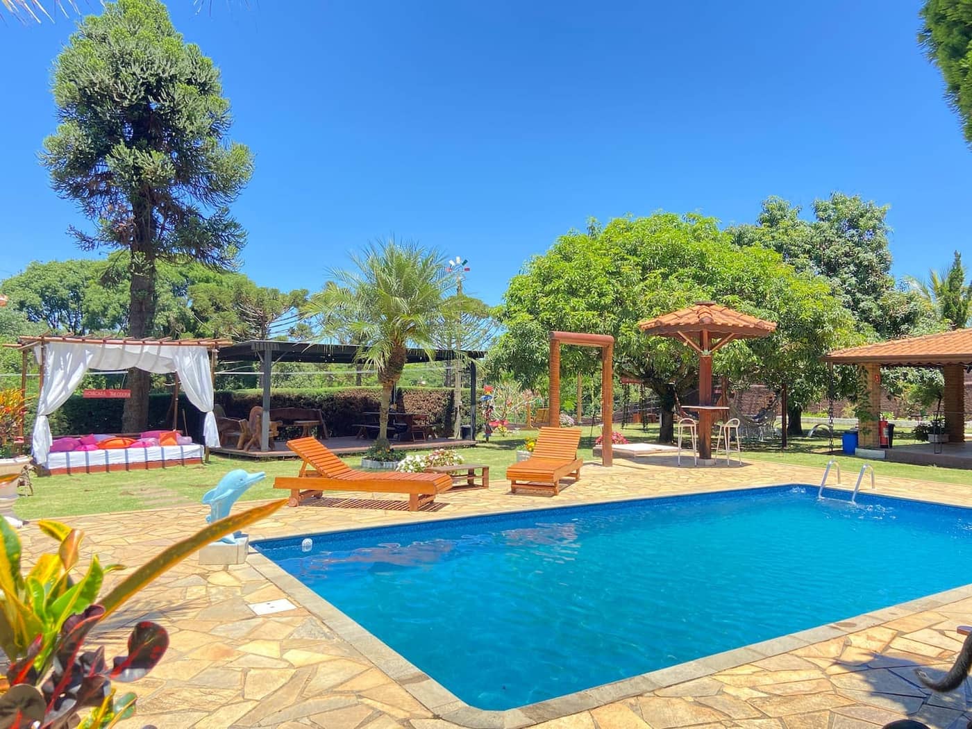 Área da piscina com gazebos e camas balinesas